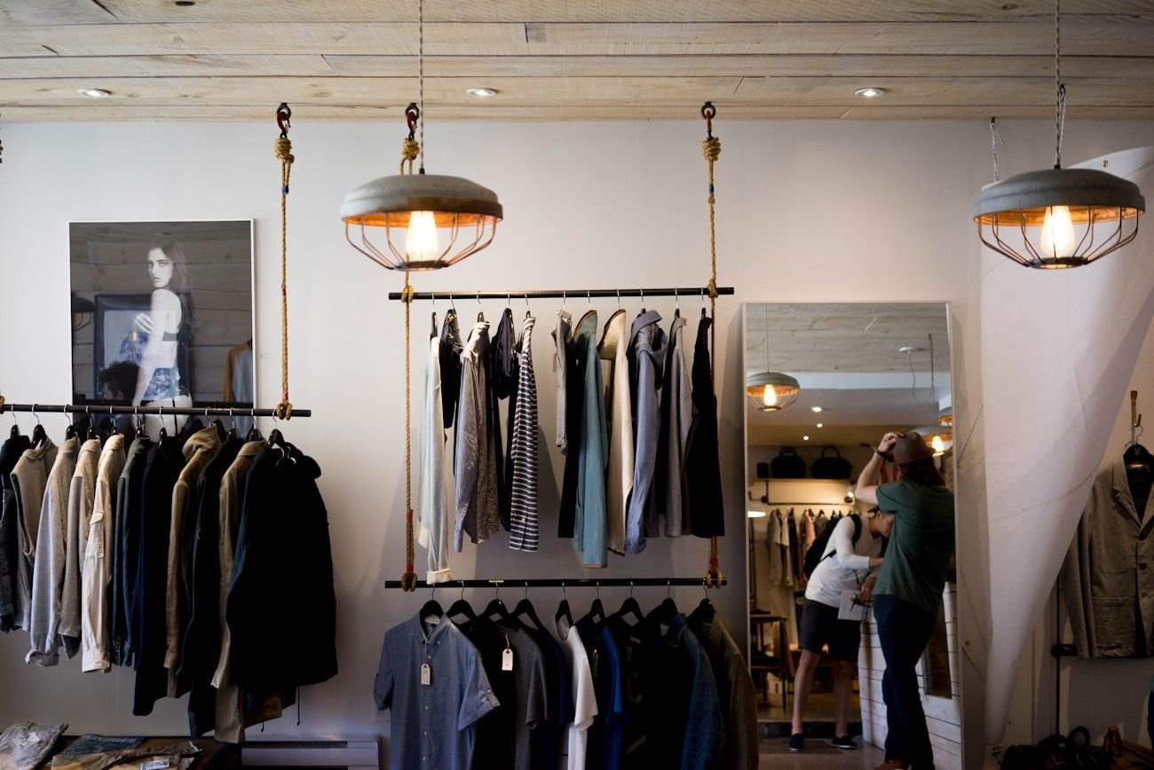 Interior of a calm boutique with garments on rails, warm lamps and a dress form