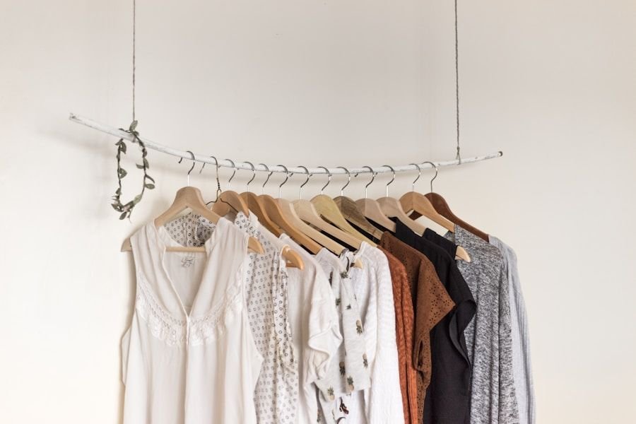 Slim rail of pale garments against a white wall in an otherwise empty room