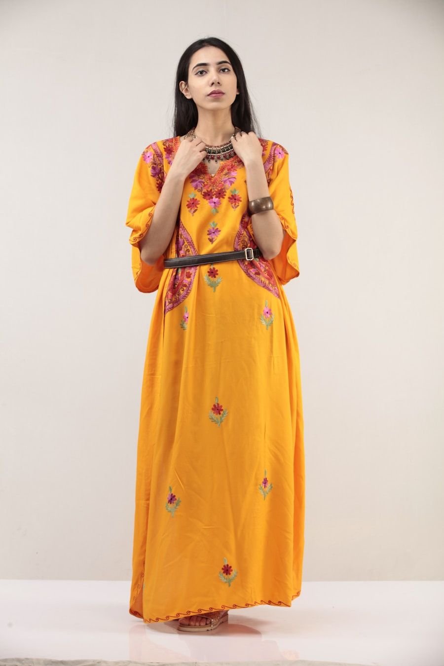 Woman wearing a long marigold silk kurta with fine embroidery down the front panel