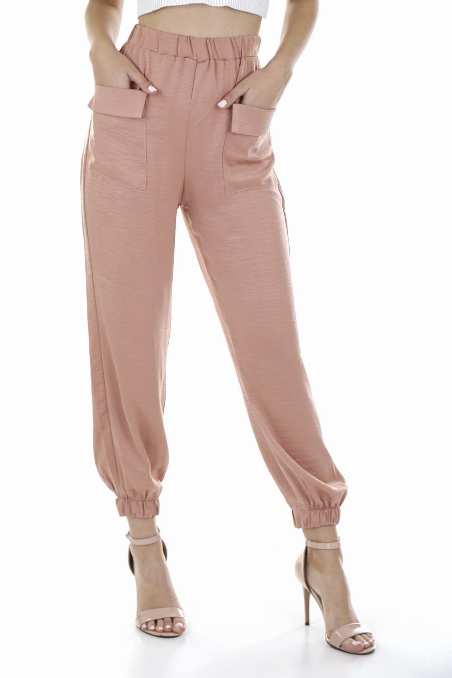 Blush silk trousers falling over the ankle above fine heeled sandals
