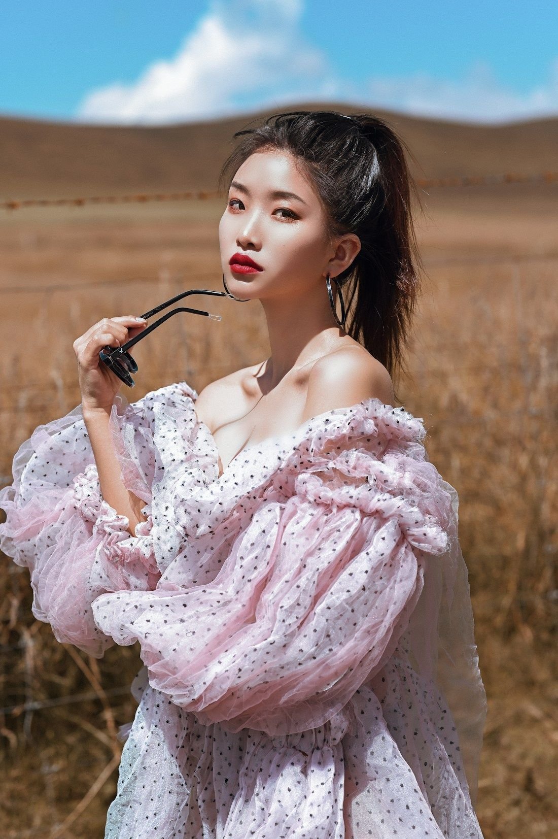 Blush silk dress with ruffled off-shoulder sleeves photographed in tall dry grass
